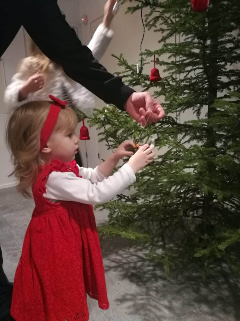 Lapsi koristelemassa joulukuusta